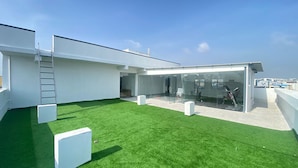 A modern rooftop with a glass enclosure, a small grassy area, and exercise equipment. - Housr 78 Madhapur Hyderabad Hitech City (Hyderabad)