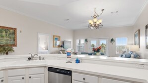 A modern kitchen with white cabinetry, a dishwasher, and a large island with a sink.