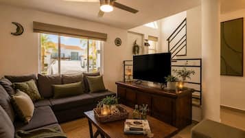 A living room with a sofa, a coffee table, a TV, and a staircase.