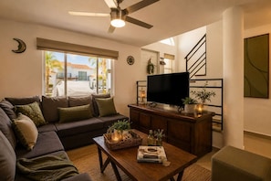 A living room with a sofa, a coffee table, a TV, and a staircase.