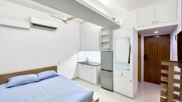 A bedroom with a bed, a desk, a wardrobe, and a door.
