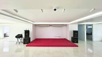 A spacious room with a red carpet, white walls, and ceiling-mounted air conditioning units.