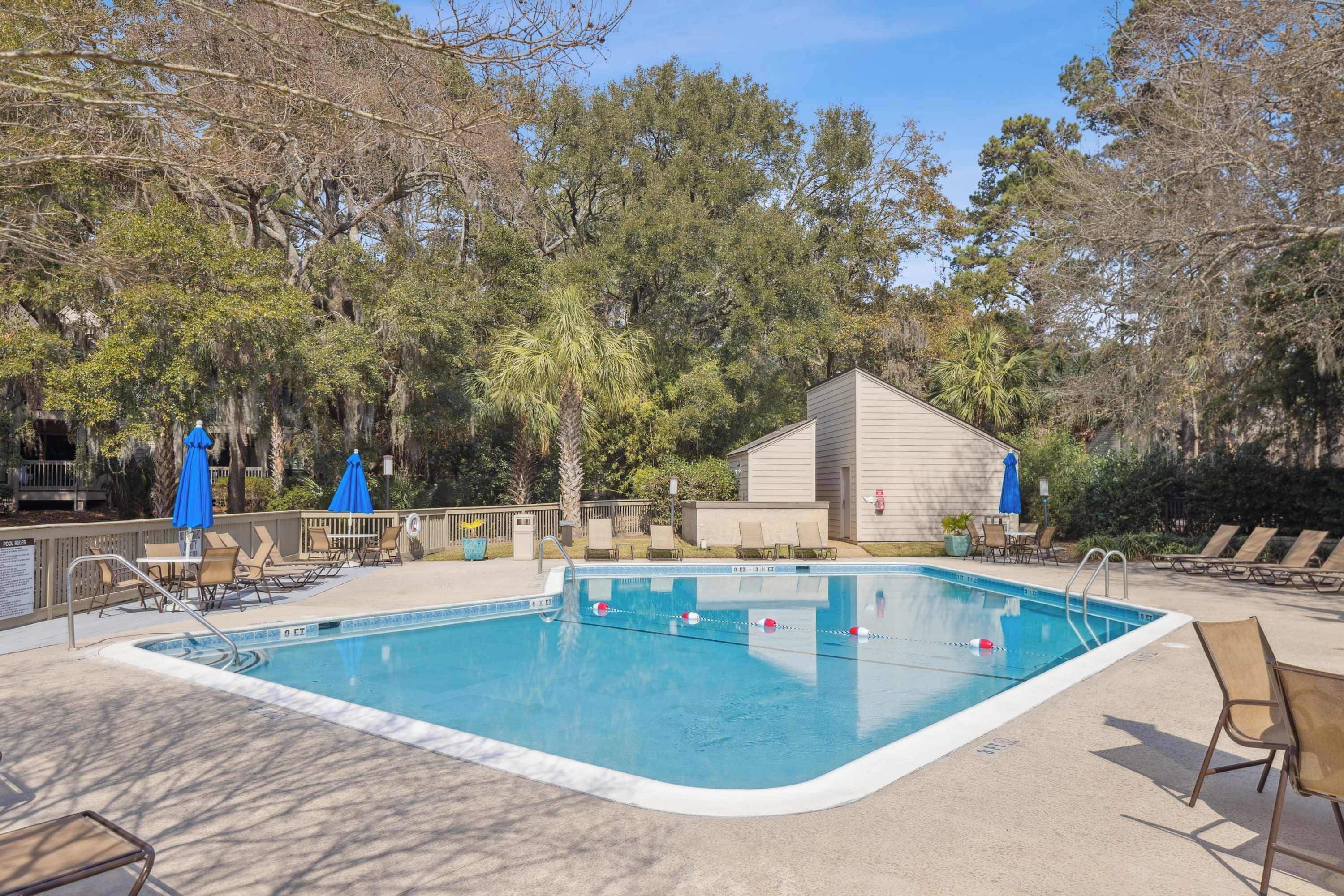 Une piscine rectangulaire à l’eau d’un bleu limpide, entourée de chaises longues et de parasols.