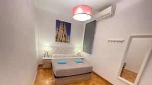 A bedroom with a bed, two bedside tables, a nightstand, a large mirror, and a painting of a cathedral. - Nuevo Roger (Barcelona)