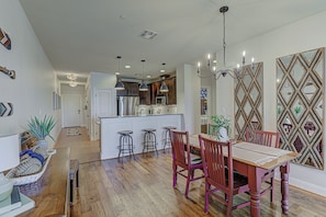 A modern kitchen with white cabinets, a central island, bar stools, and pendant lighting.