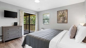 A bedroom with a bed, a dresser, a television, a window, and a painting. - Quittin' Time - Stay for 6 with Golf Course Views & Resort Amenities (Branson)