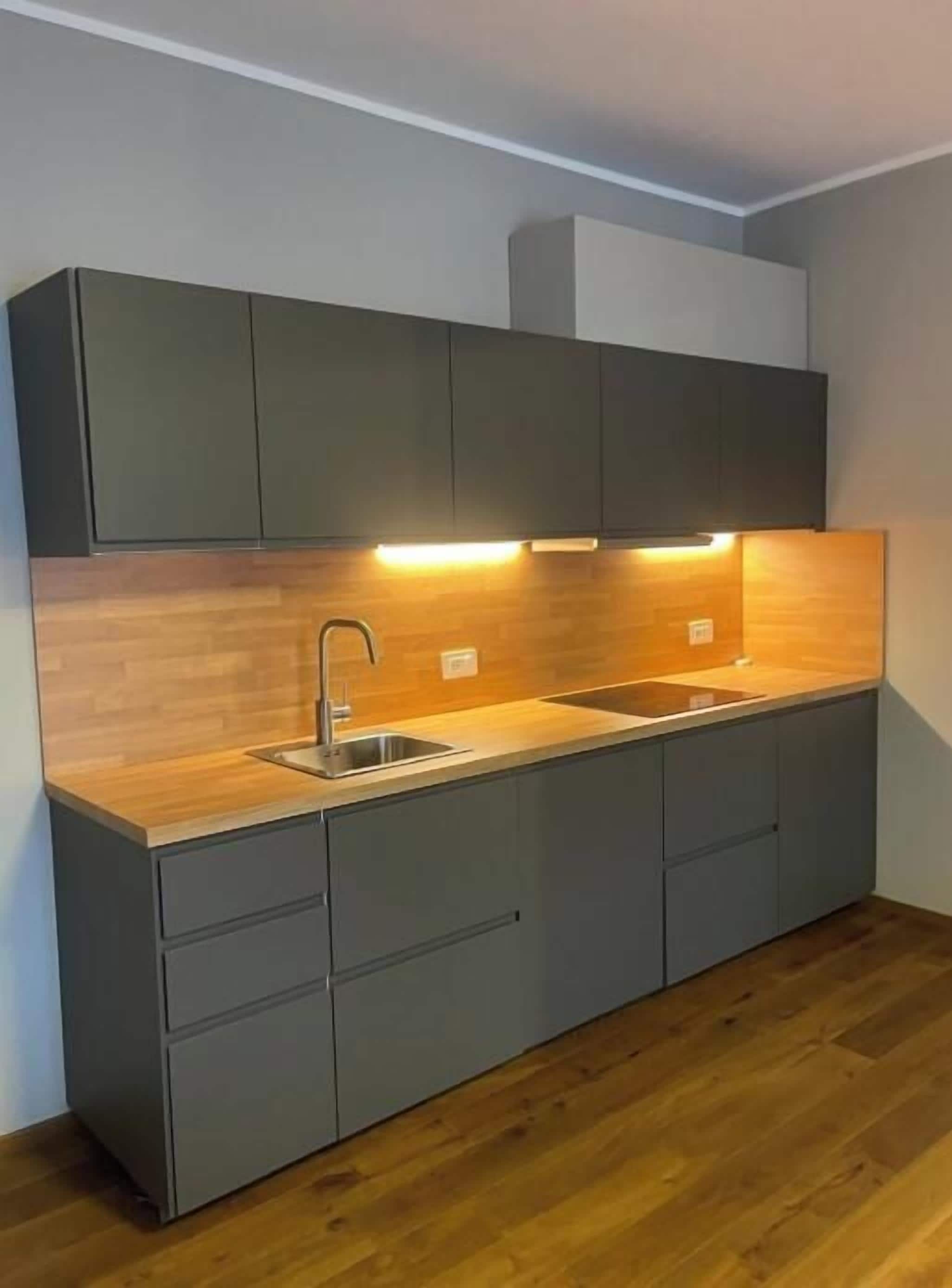 A modern kitchen with a wooden countertop, a sink, and built-in cabinets.