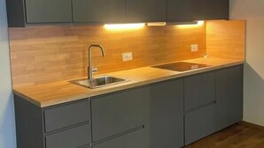 Una cucina moderna con mobili scuri, un piano di lavoro in legno e illuminazione sotto i pensili.