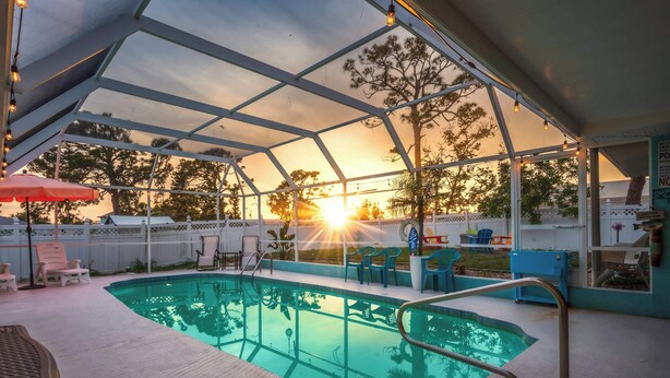 An indoor swimming pool with a glass ceiling, surrounded by lounge chairs and a red umbrella. - Heated Pool Pet Friendly Arcade games Bikes (Englewood)