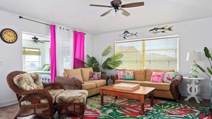 A living room with a sofa, chairs, a coffee table, and a large window with curtains. - Heated Pool Pet Friendly Arcade games Bikes (Englewood)