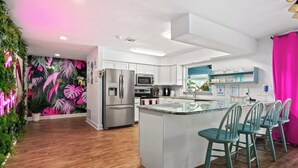 A modern kitchen with white cabinets, stainless steel appliances, and a central island with bar stools. - Heated Pool Pet Friendly Arcade games Bikes (Englewood)