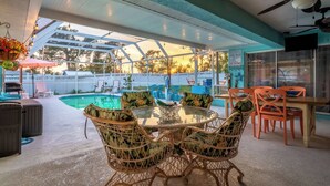 A covered outdoor area with a pool, dining table, chairs, and a ceiling fan. - Heated Pool Pet Friendly Arcade games Bikes (Englewood)