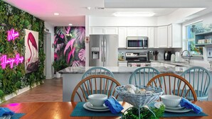A modern kitchen with white cabinets, stainless steel appliances, and a neon 'Welcome' sign. - Heated Pool Pet Friendly Arcade games Bikes (Englewood)