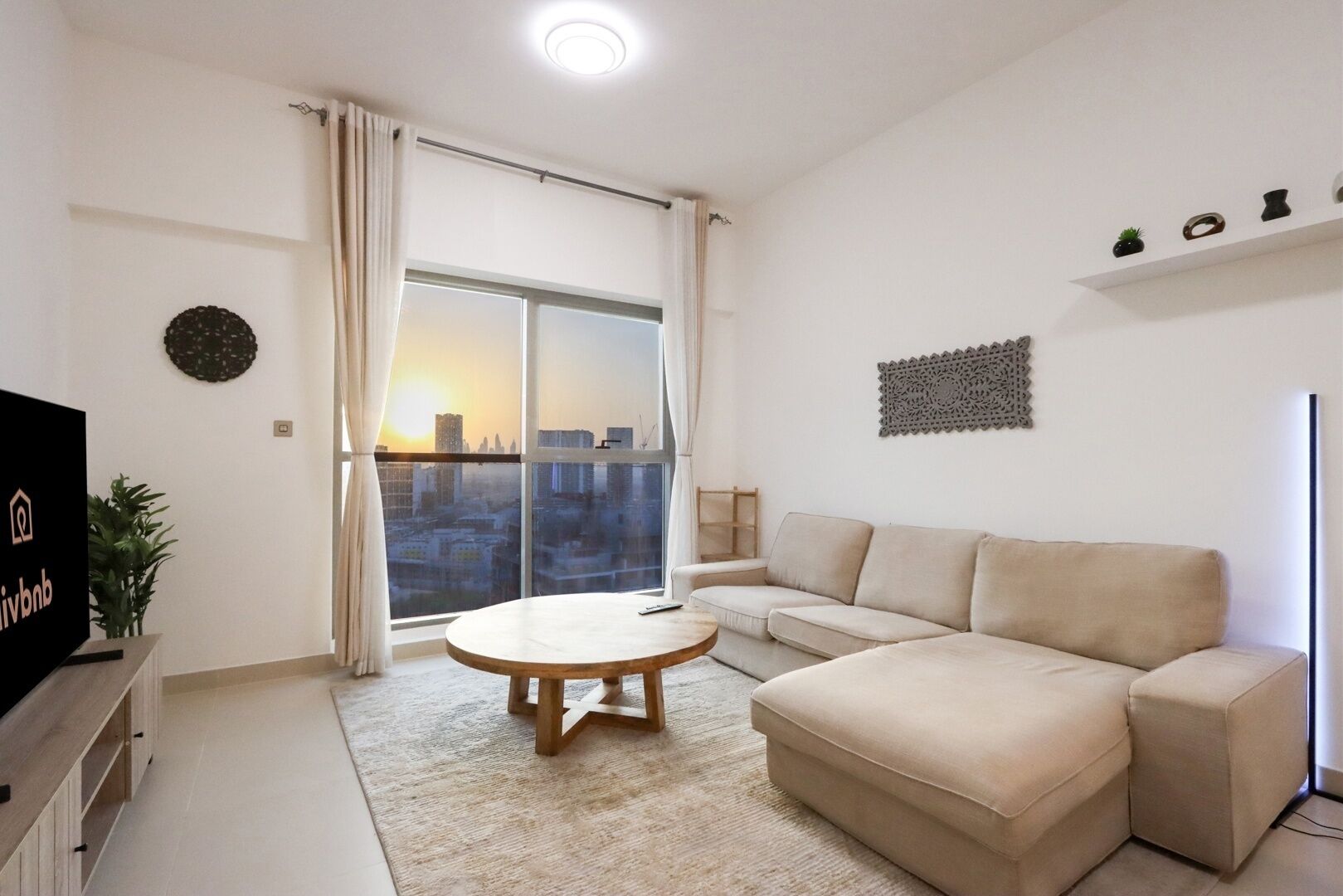 Ein modernes Wohnzimmer mit einer Couch, einem Couchtisch und einem Fernseher auf einem Holzboden.