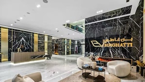 A modern lobby with a reception desk, seating area, and a fireplace. - Luxury 2BR with Canal View Burj Khalifa view and Infinity Pool Access (Business Bay)