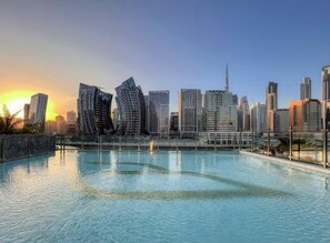 A modern cityscape with skyscrapers and a large swimming pool.