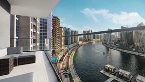A high-rise building with a balcony overlooking a river, modern architecture, and a clear sky. - Luxury 2BR with Canal View Burj Khalifa view and Infinity Pool Access (Business Bay)