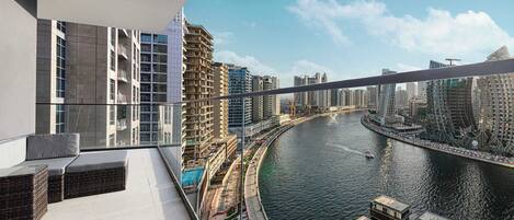 A high-rise building with a balcony overlooking a river, modern architecture, and a clear sky.