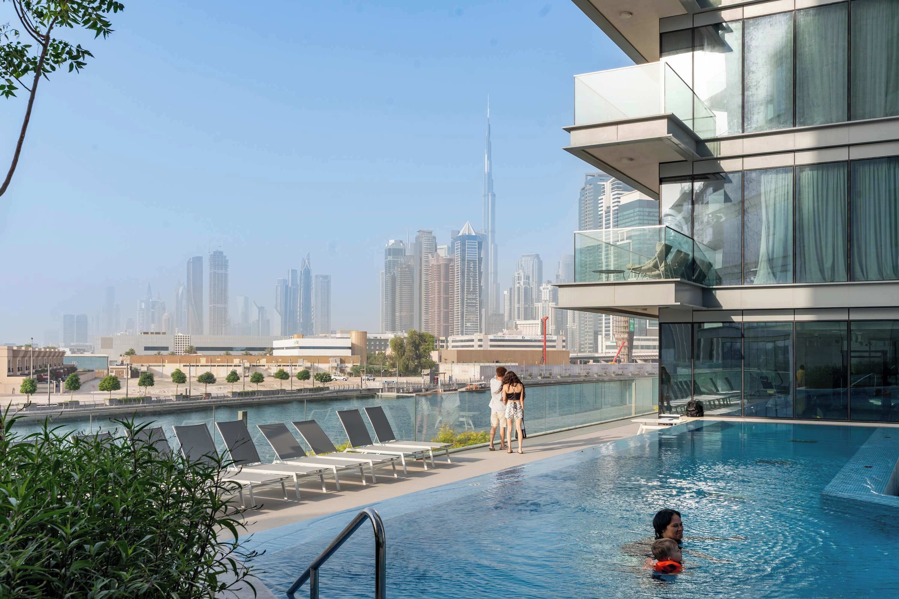 A rooftop pool with a view of the city skyline, including the Burj Khalifa.