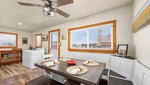 A compact kitchen with a dining area, wooden flooring, and a ceiling fan.