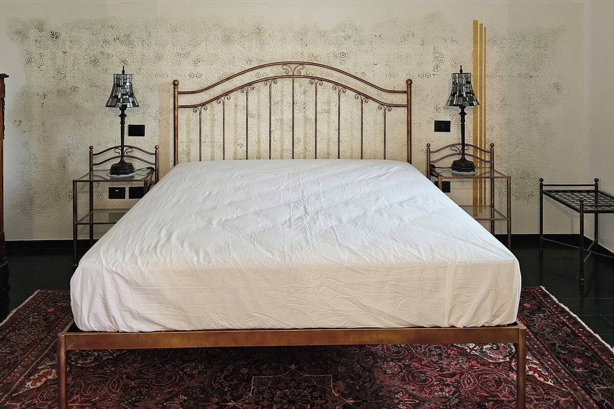 Ein Schlafzimmer mit einem hölzernen Bett, gemustertem Wandpapier und einem roten Teppich.