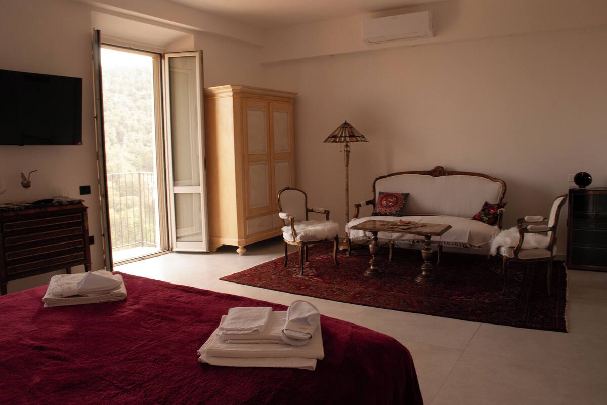 Ein Hotelzimmer mit einem großen Bett, einer Couch, einem Esstisch und einem Kleiderschrank.
