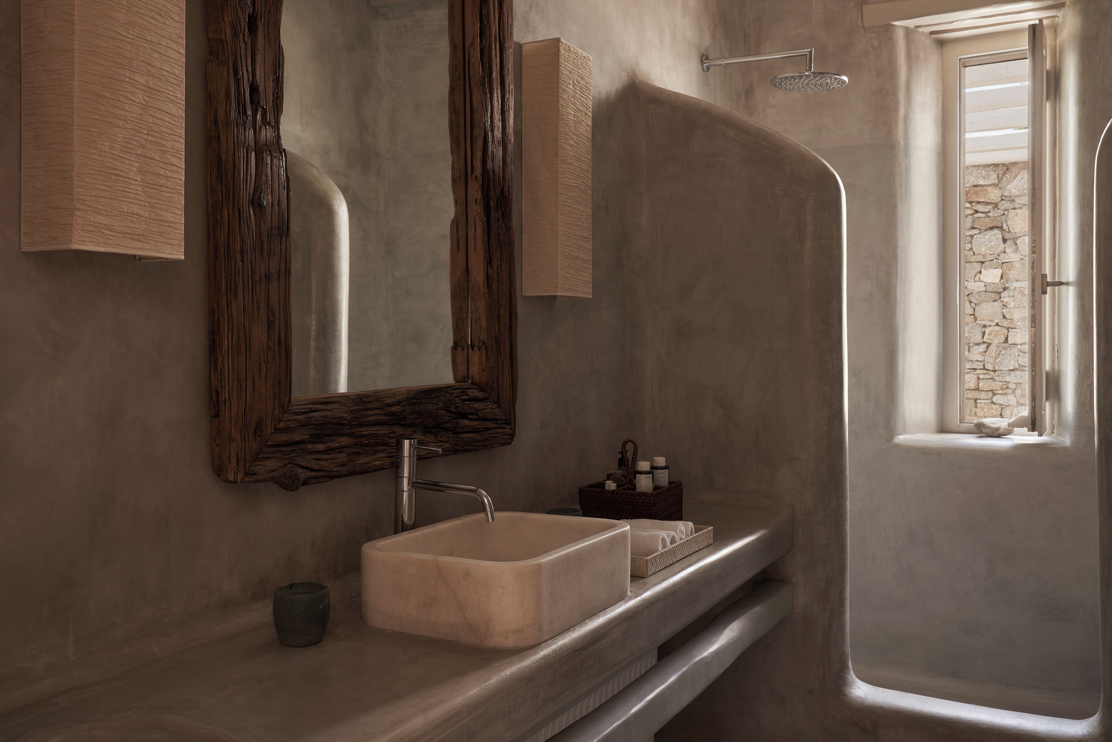 A bathroom with a large mirror, a sink, a shower, and a stone wall.