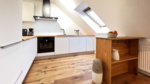 Een moderne keuken met witte kasten, een houten aanrechtblad en een dakraam.
