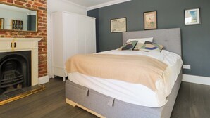 A bedroom with a bed, a fireplace, a wardrobe, and a map on the wall. - Fairhazel Apartment (Hastings)