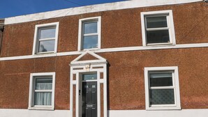 A two-story building with a symmetrical facade, featuring a central entrance with a black door and white trim. - Fairhazel Apartment (Hastings)