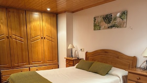 Une chambre à coucher avec un lit en bois, une table de chevet, une lampe et une armoire.