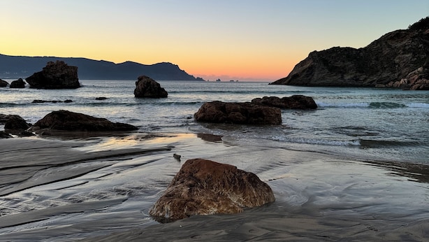 Une plage avec de gros rochers et une eau calme.