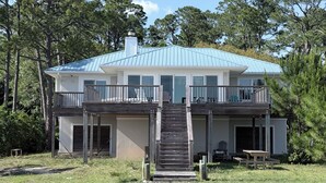 A two-story house with a front porch, a staircase leading to the entrance, and a metal roof.