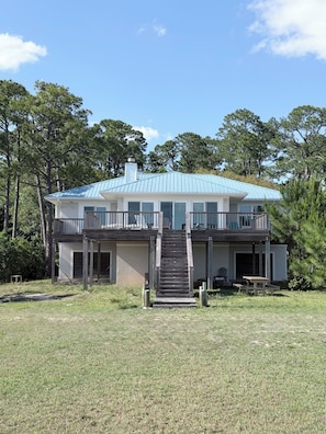 A two-story house with a front porch, a staircase leading to the entrance, and a metal roof.