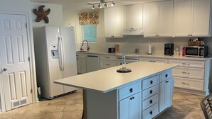 A modern kitchen with white cabinets, a central island, and a built-in microwave.