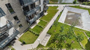 Vista aérea de un edificio moderno con un patio, una fuente de agua y un camino pavimentado.