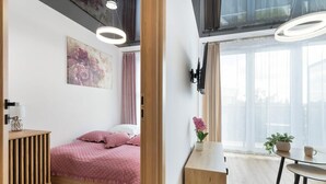 Un dormitorio con cama, mesita de noche y ventana con cortinas.