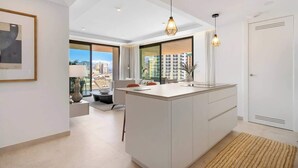 Een moderne keuken met een centraal eiland, hanglampen en uitzicht op de stad.