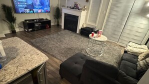 Een moderne woonkamer met een televisie, open haard en zithoek.
