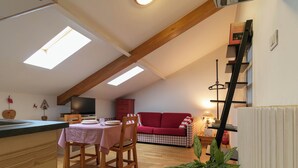 Ein gemütliches Loft mit Essplatz, einem roten Sofa und einer Pflanze.