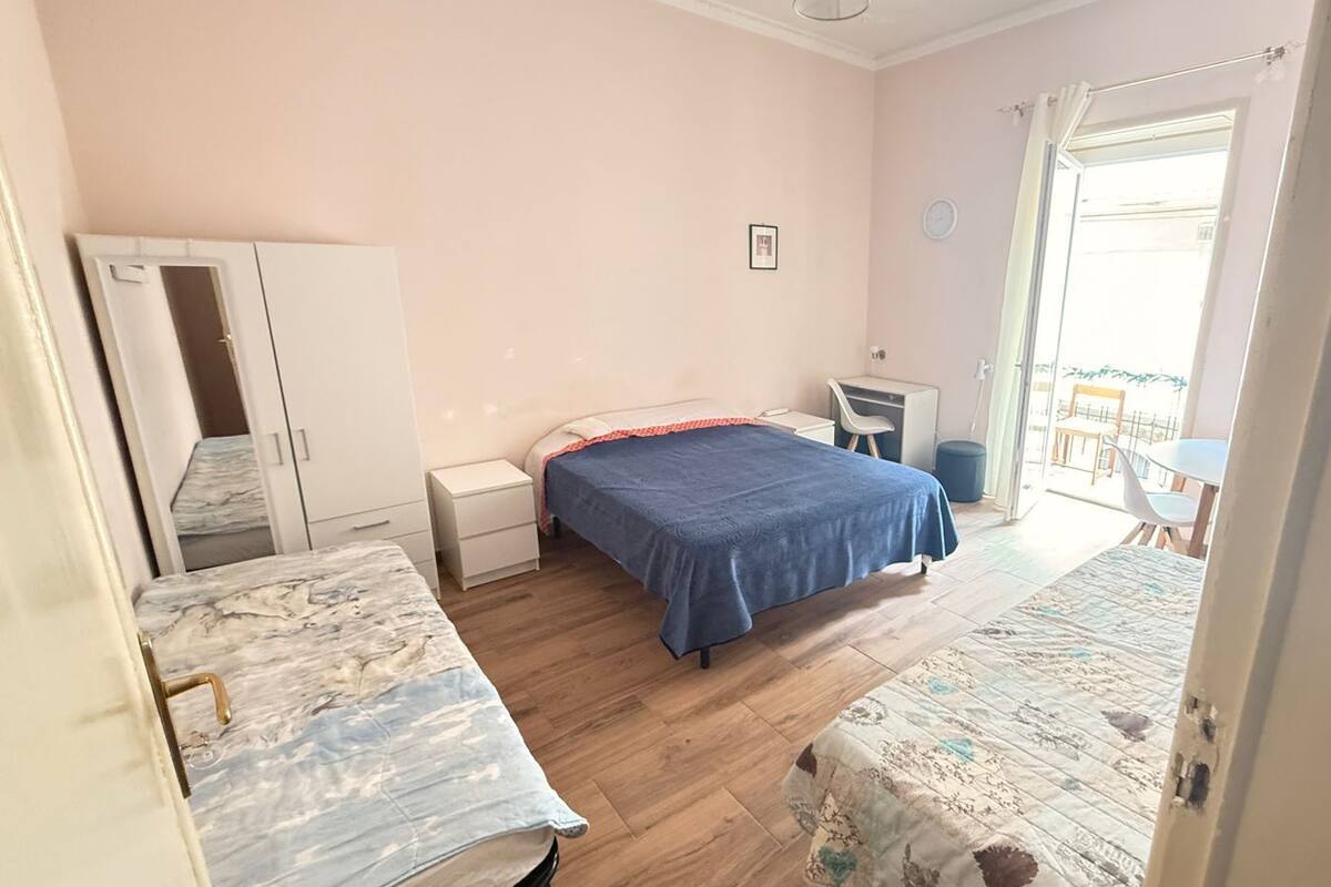 A bedroom with a bed, a desk, a chair, and a wardrobe.