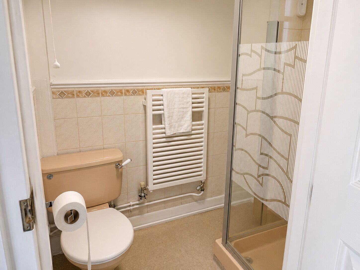 A bathroom with a toilet, a towel rack, and a shower area.