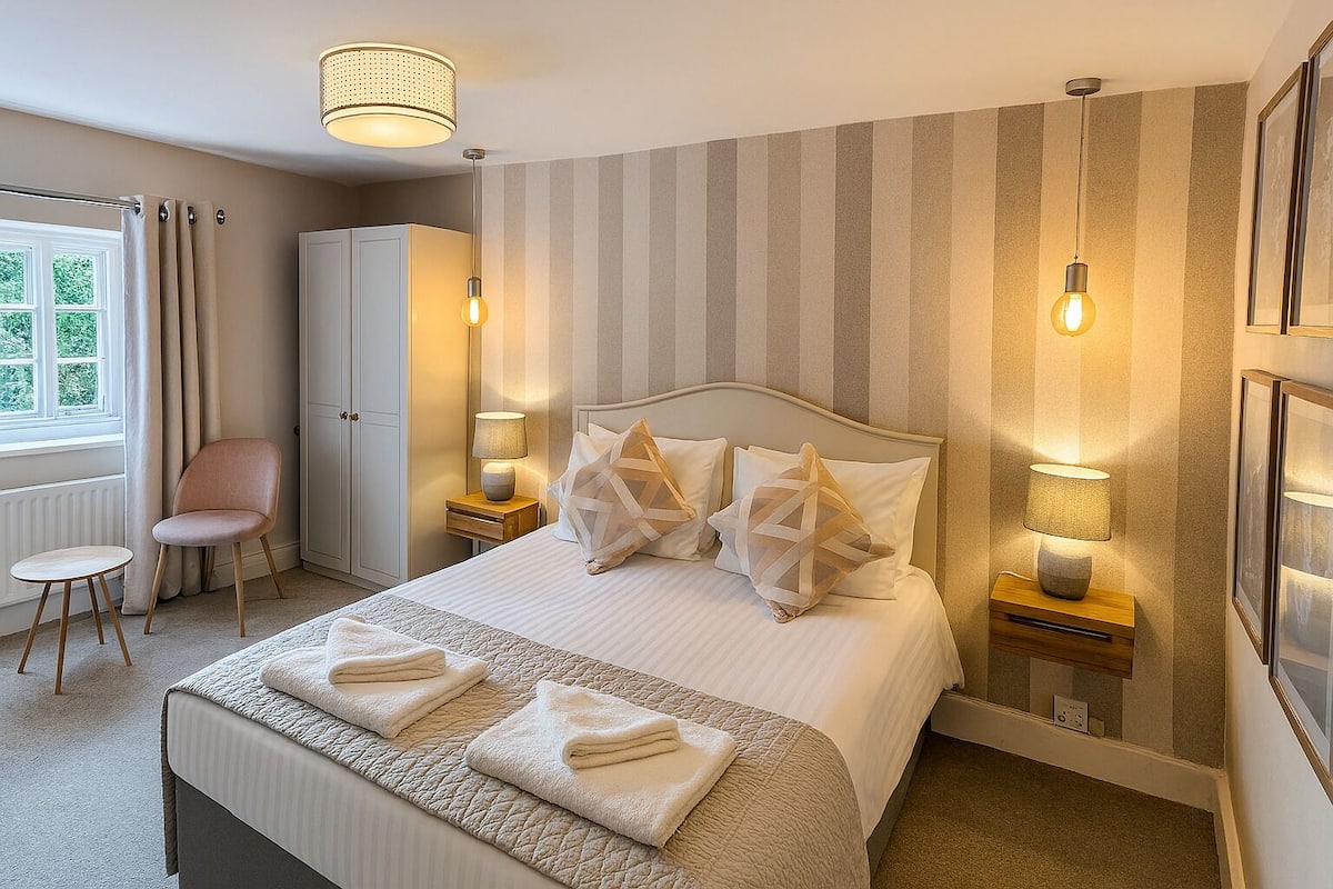 A neatly arranged bedroom with a large bed, bedside lamps, a chair, and a wardrobe.