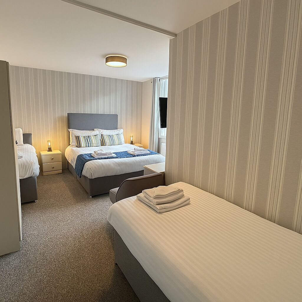 Une chambre d’hôtel avec un grand lit, un lit plus petit, un bureau et une chaise.