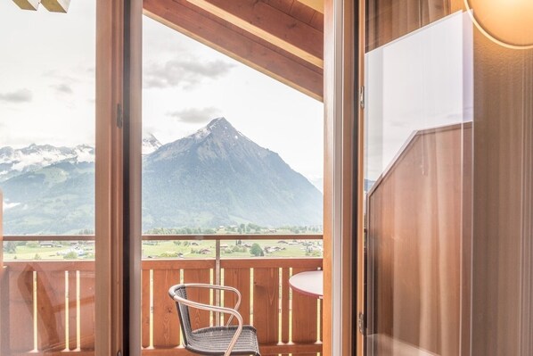 Un balcon avec vue sur une montagne, une chaise et une table.
