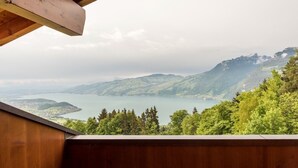 A view from a wooden balcony overlooking a lake surrounded by mountains and dense forest. - Auszeit-Hotel Z Aeschiried (Retreat Hotel Z Aeschiried) (Aeschi bei Spiez)