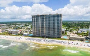 A high-rise hotel with multiple floors, a beachfront location, and a pool area.