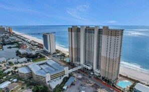 A high-rise hotel with multiple floors, a beach view, and a parking structure.