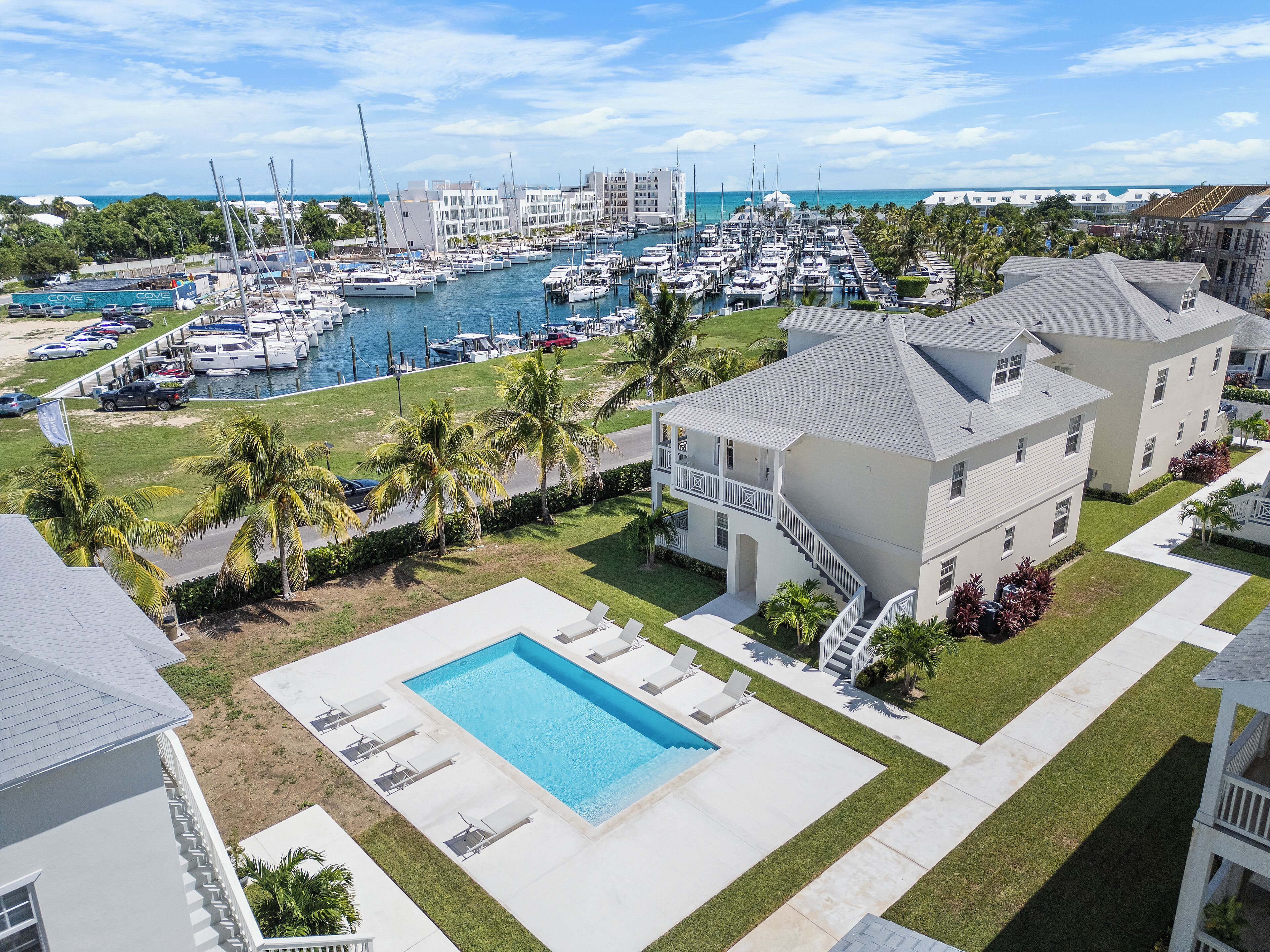 Un quartier résidentiel doté d’une piscine, d’un port de plaisance avec des bateaux et offrant une vue sur l’océan.