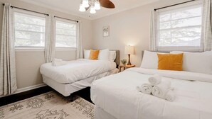 Une chambre d’hôtel avec deux lits, un ventilateur de plafond et une fenêtre avec des rideaux.